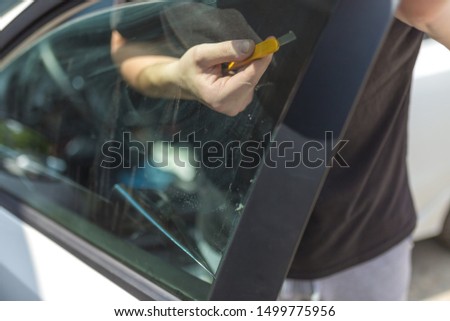 Close up shot hands of man removing old car window film