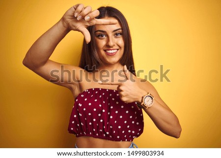 Young beautiful woman wearing red t-shirt standing over isolated yellow background smiling making frame with hands and fingers with happy face. Creativity and photography concept.