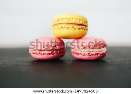Sweet colorful French macaroon cookies dessert on black stone surface over white wooden background