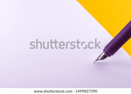 A pen with an ink pen writes text, a letter, a note or makes another note on a white sheet of paper that lies on an orange background