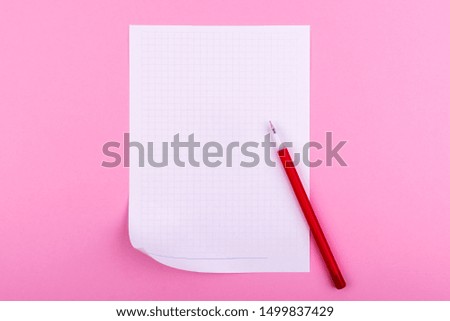 A white sheet of paper for drawings, texts, letters and notes, next to a red pen lies on a pink background