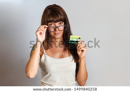 Finance and Bank cards. A young woman in glasses with tattoos on her hand holding a Bank card. Copy space