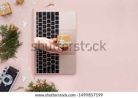 Top view of hand with a gift from laptop. Festive flat lay on pink background