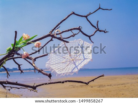 Bohemian photoshoot location with upside down white umbrella, florals ans beach backdrop 