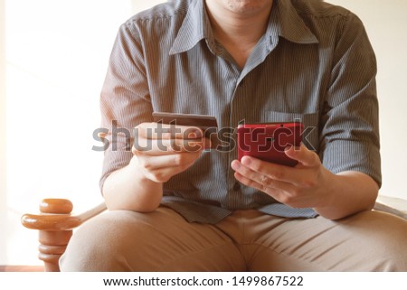 business man holding credit card and using mobile phone on sofa for online shopping