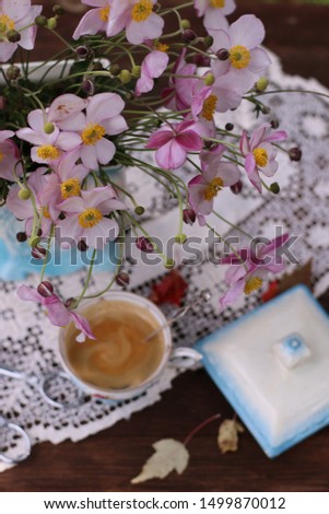 Coffee in antique china cup with silver spoon, autumn anemones, vintage style, vertical photo, daylight