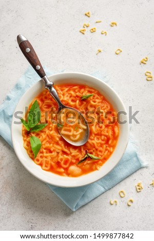 Alphabet Tomato Soup. Vegetable soup with alphabet pasta on white background, copy space, top view. Minestrone soup for kids. Royalty-Free Stock Photo #1499877842