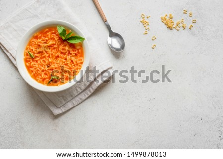 Alphabet Tomato Soup. Vegetable soup with alphabet pasta on white background, copy space, top view. Minestrone soup for kids. Royalty-Free Stock Photo #1499878013