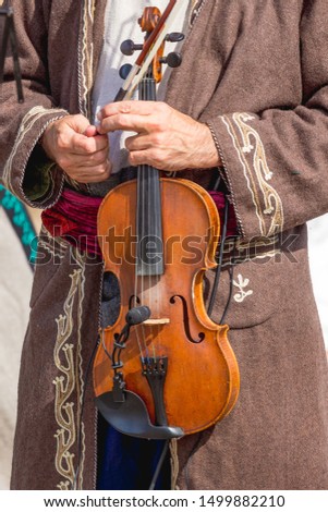 Musician in an old costume holds a violin in his hands
