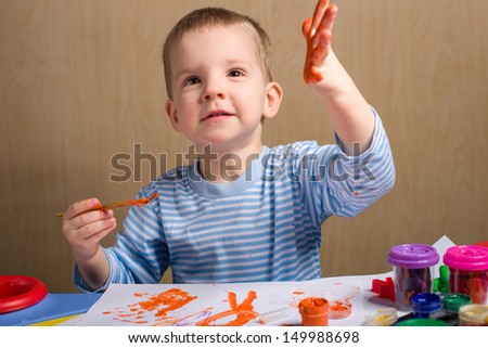 Cute little boy painting at the table