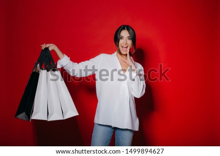 Excited beautiful woman with a lot of shopping bags, Black Friday shopping, isolated on red