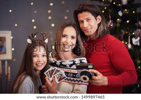 Beautiful family celebrating Christmas at home and taking instant pictures