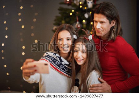 Beautiful family celebrating Christmas at home and taking selfie