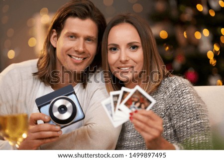 Beautiful couple celebrating Christmas at home and taking instant pictures
