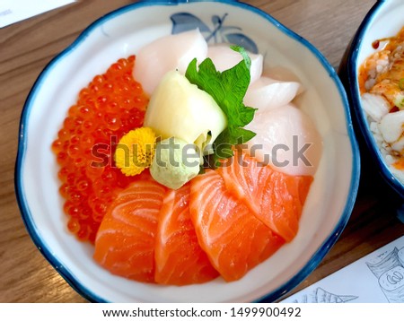 Japanese food pictures Rice with Mixed Sushi Salmon fillet, Salmon roe, fresh scallops Served with wasabi and pickled ginger, placed on oba leaves in a round cup, placed on a wooden table