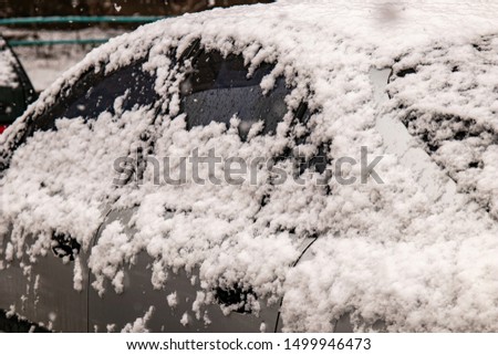 Gray Car covered with snow in the winter blizzard.Extreme snowfall