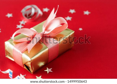 Luxurious gold gift box with pink ribbon, isolated on red background. Christmas, party, birthday.