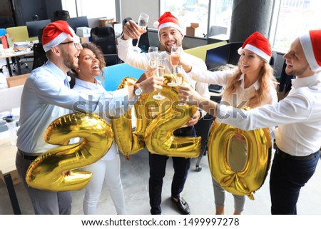 Office business coworkers celebrating winter holidays together at work and drinking champagne in office. Merry Christmas and Happy New Year.
