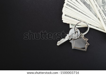 House keys over the hundred dollar banknotes against wooden background
