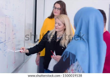 Female Architecture teacher at work. Female professor explain architectural projects to students. Beautiful female university architecture professor explain lessons to multiethnic students.