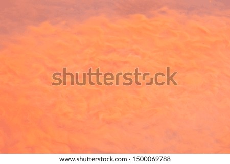 The background is caused by turbid water because the currents blow the red dust. Orange dust flows and adheres to the water.
