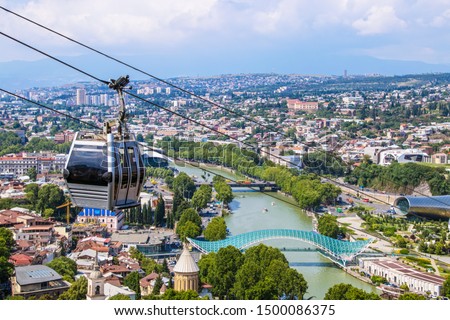 View of cable car above Tbilisi Georgia with view of Mtkvari - Kura River and Peace Bridge and city with mountains in the distance Royalty-Free Stock Photo #1500086375