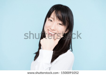 Young business woman giving thumb up gesture, against light blue background