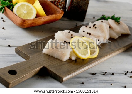 White raw fish on a wooden cutting board, halibut fillet, cooking seafood for lunch, dinner or supper