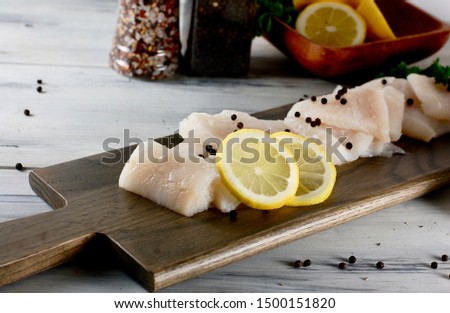 White raw fish on a wooden cutting board, halibut fillet, cooking seafood for lunch, dinner or supper