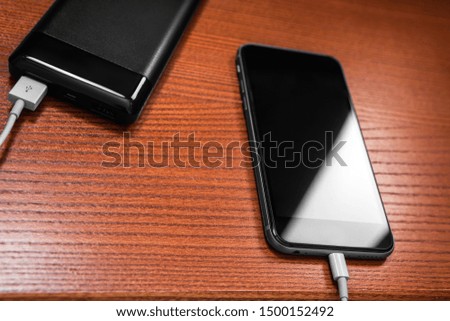 powerbank charges smartphone isolated on wood background