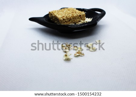Kozinaki oatmeal in a black saucer on a white background
