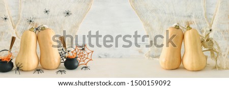 holidays image of Halloween. Pumpkins, witcher cauldron, broom, treats over white wooden table
