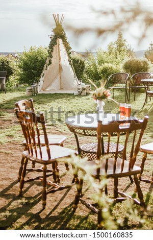 Wooden fabric wigwam decorated with green eucalyptus branches in backyard, event or wedding in boho style