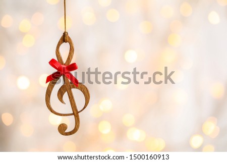 Wooden treble clef against blurred lights, space for text. Christmas music