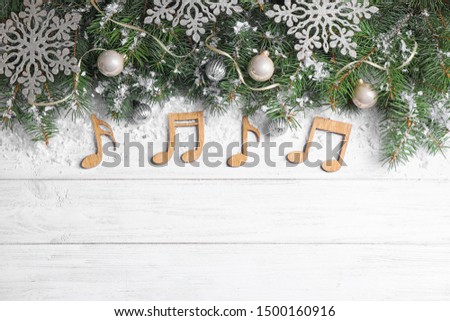 Flat lay composition with Christmas decor and music notes on white wooden table, space for text