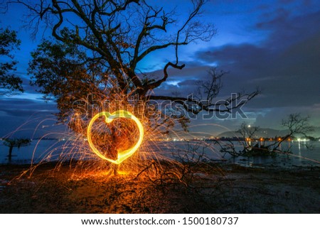 burning steel wool under mangrove tree in heart shape in twilight at Klong Mudong Phuket Thailand.