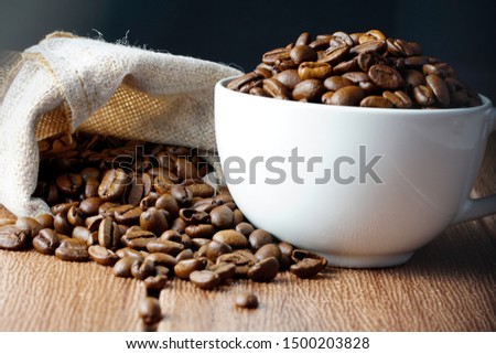 Closeup Coffee Bean next to the white cup isolated white background for International Coffee Day Celebration. 