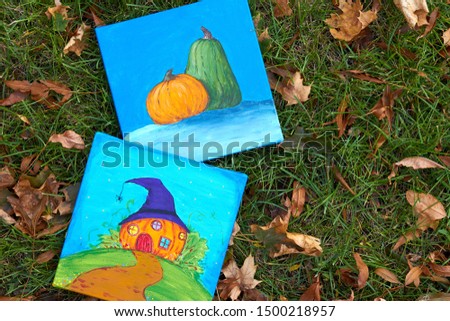 Two paintings (picture) with pumpkins (Jack-o'-lantern) and Happy Halloween theme on green grass with autumn leaves