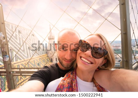 Young, happy couple of tourists taking a selfie against the background of the panorama of the city at sunset from the North Tower of St. Stephen's Cathedral in Vienna, Austria