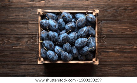 Close up of ripe plums in a wooden crate.