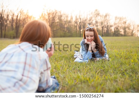 Two girls lie on the grass and shooting photos.