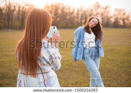 Two young women shooting photos outdoors. Best friends