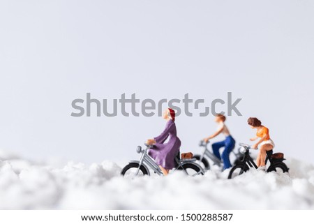Miniature people : Travelers riding a bicycle on snow , winter background concept