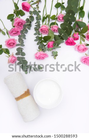 Spa setting with eucalyptus twig leaves with set of pink rose and rolled towel, cream in bowl,Copy space
