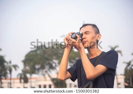 a teenager is taking pictures in the city with an analog camera
