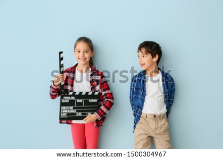 Cute little children with movie clapper on color background