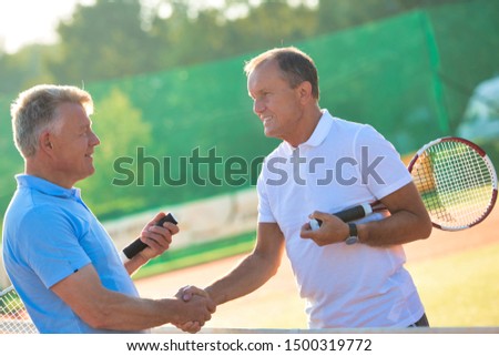 Senior tennis player shaking hands in court