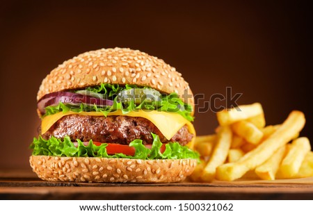 fresh cheeseburger with french fries on wooden table