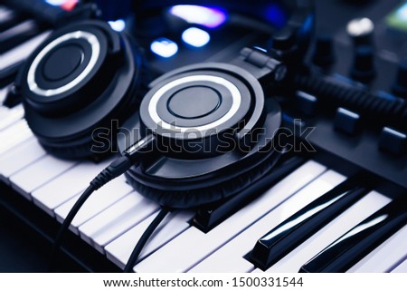 Music background.Play & listen to musical tracks with headphones & synthesizer piano board.Professional studio setero headset and synth keyboard.Compose songs with high quality analog audio equipment Royalty-Free Stock Photo #1500331544
