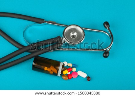 Picture of medical supplies: stethoscope, bottle of medication, thermometer, etc. on blue background - top view